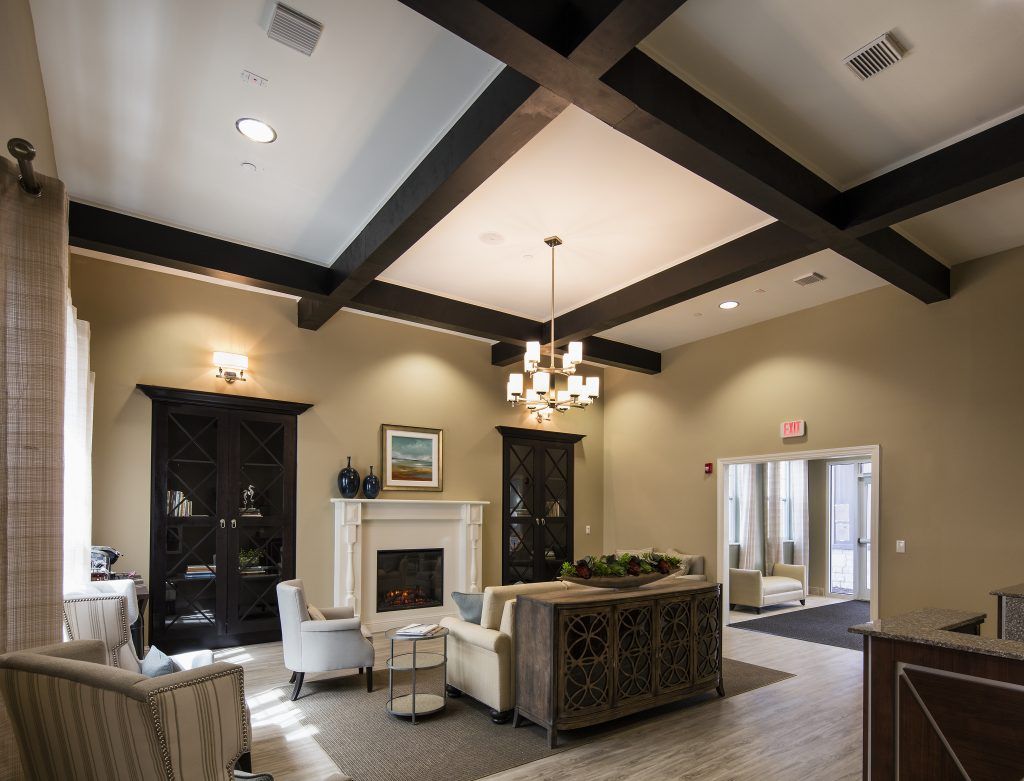 A modern living room with a cozy seating area, featuring a central fireplace and elegant chandelier.