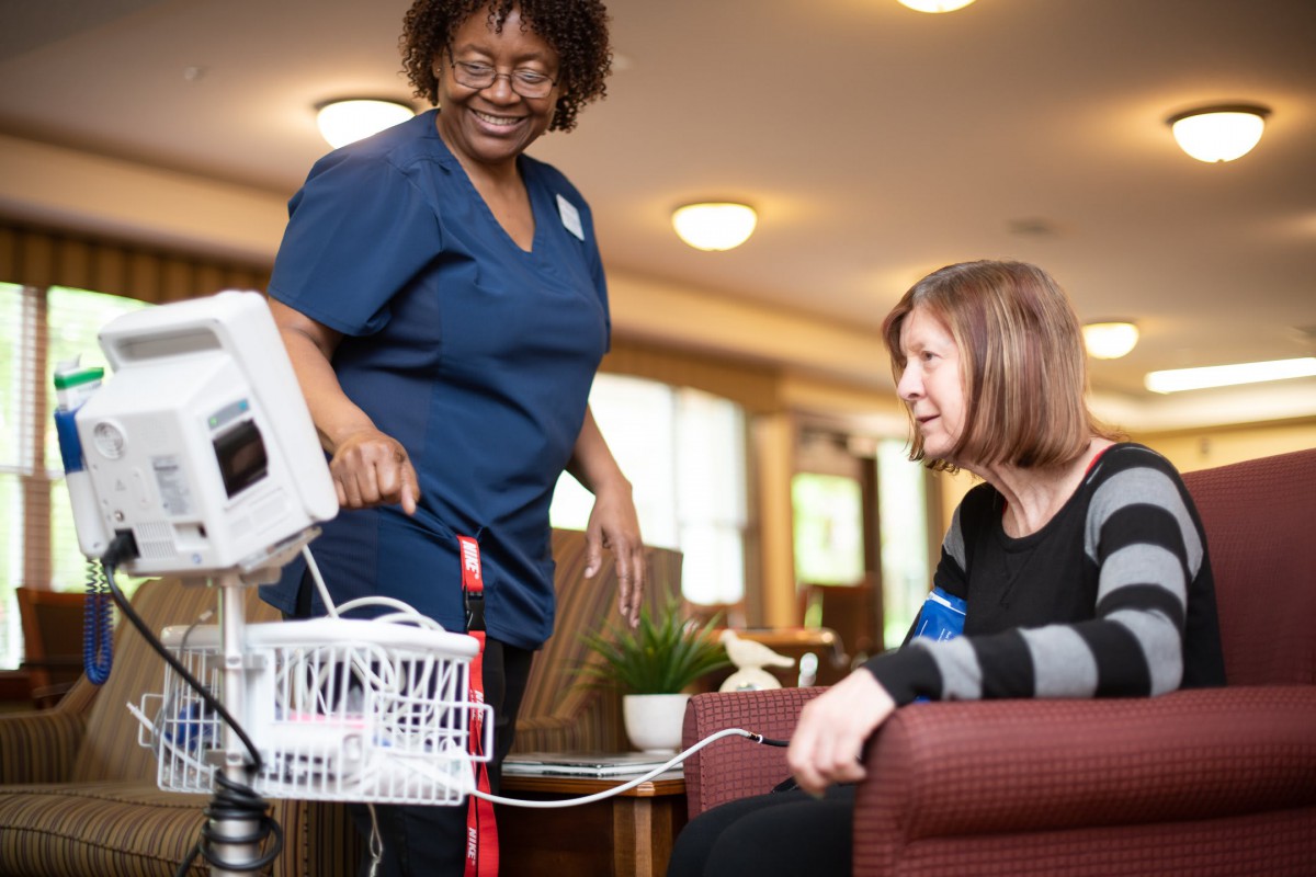 A nurse is using medical equipment to check the blood pressure of a patient.