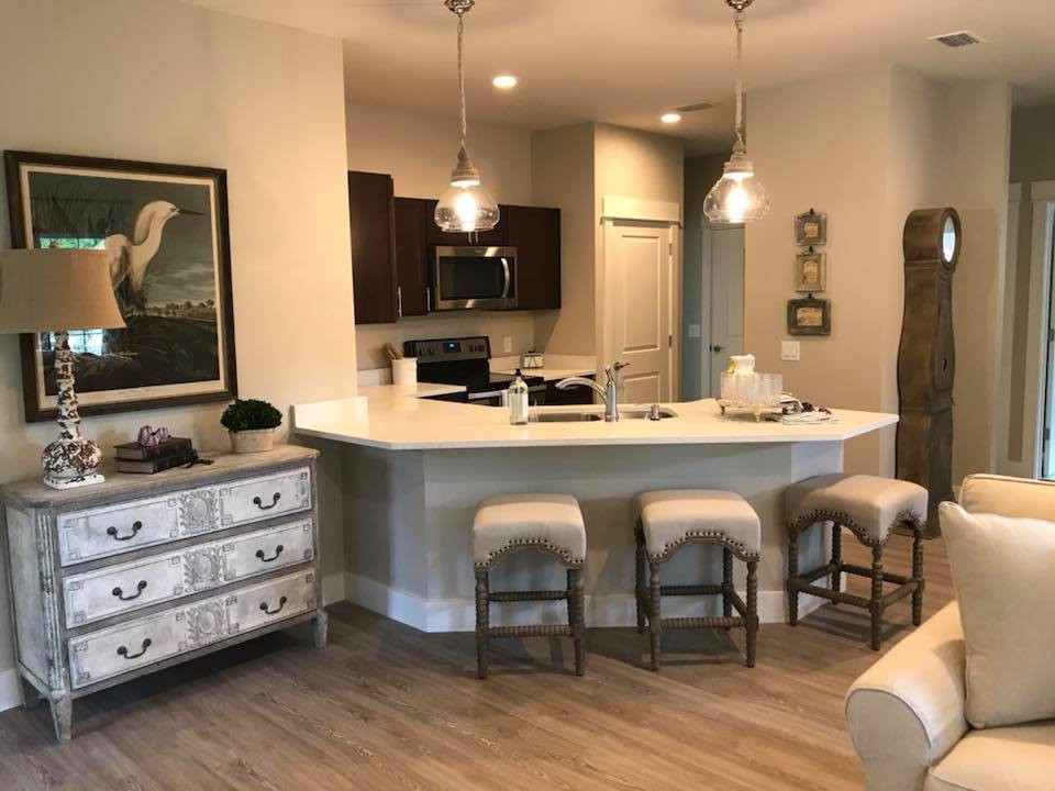 A modern kitchen with a white countertop, bar stools, and pendant lighting.