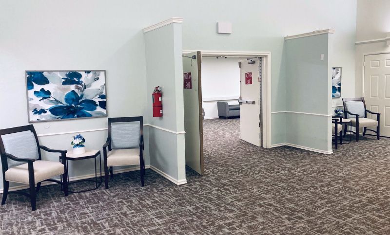 An open doorway leading into a room, with chairs and artwork in a hallway.