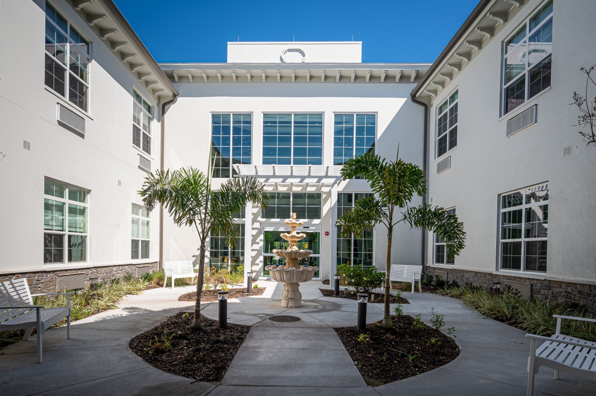 A modern building courtyard featuring a central fountain and palm trees.