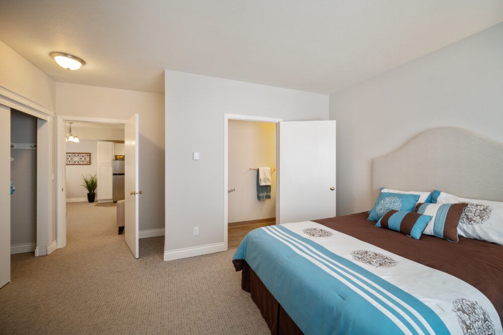 A modern bedroom featuring a neatly made bed with blue and brown bedding, complementing the overall minimalist interior design.