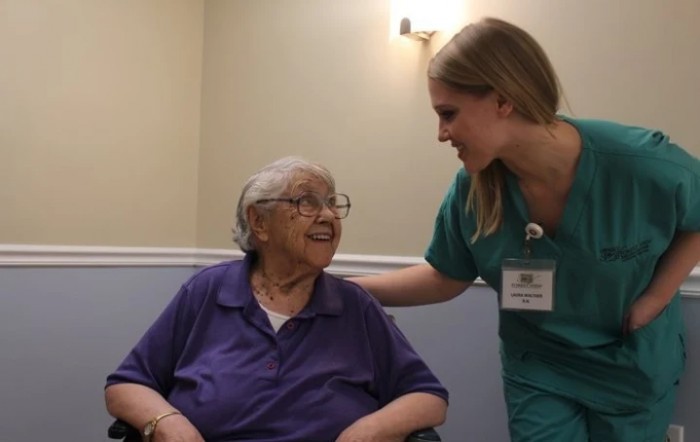 A nurse providing support and care to an elderly woman in a healthcare setting.