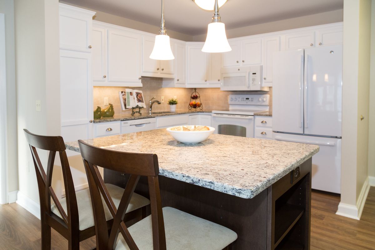 A modern kitchen featuring a central island with a granite countertop and pendant lighting.