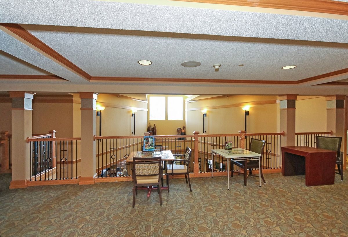 A spacious lobby area with chairs and tables arranged on a carpeted floor.