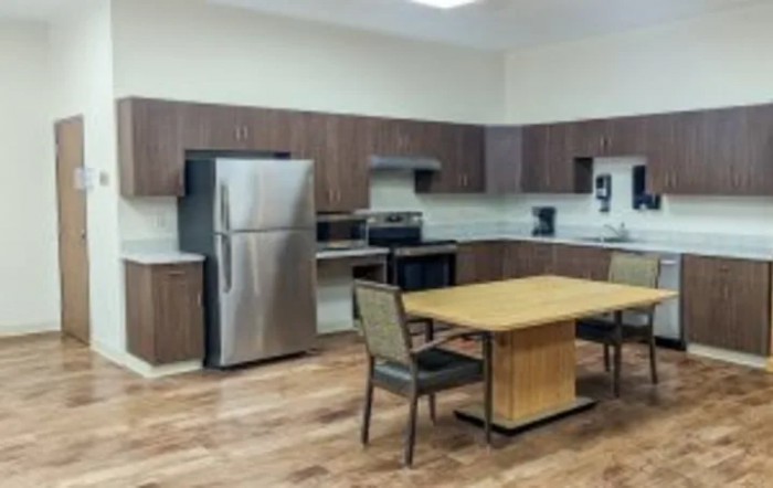 A modern kitchen with wooden cabinetry, stainless steel appliances, and a dining table.