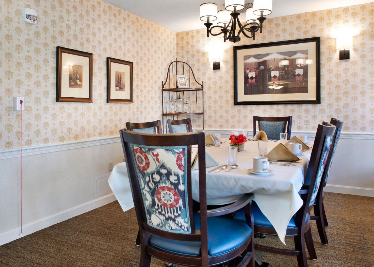 A cozy dining room featuring a round table with stylish chairs, adorned with a chandelier and decorative wall art.