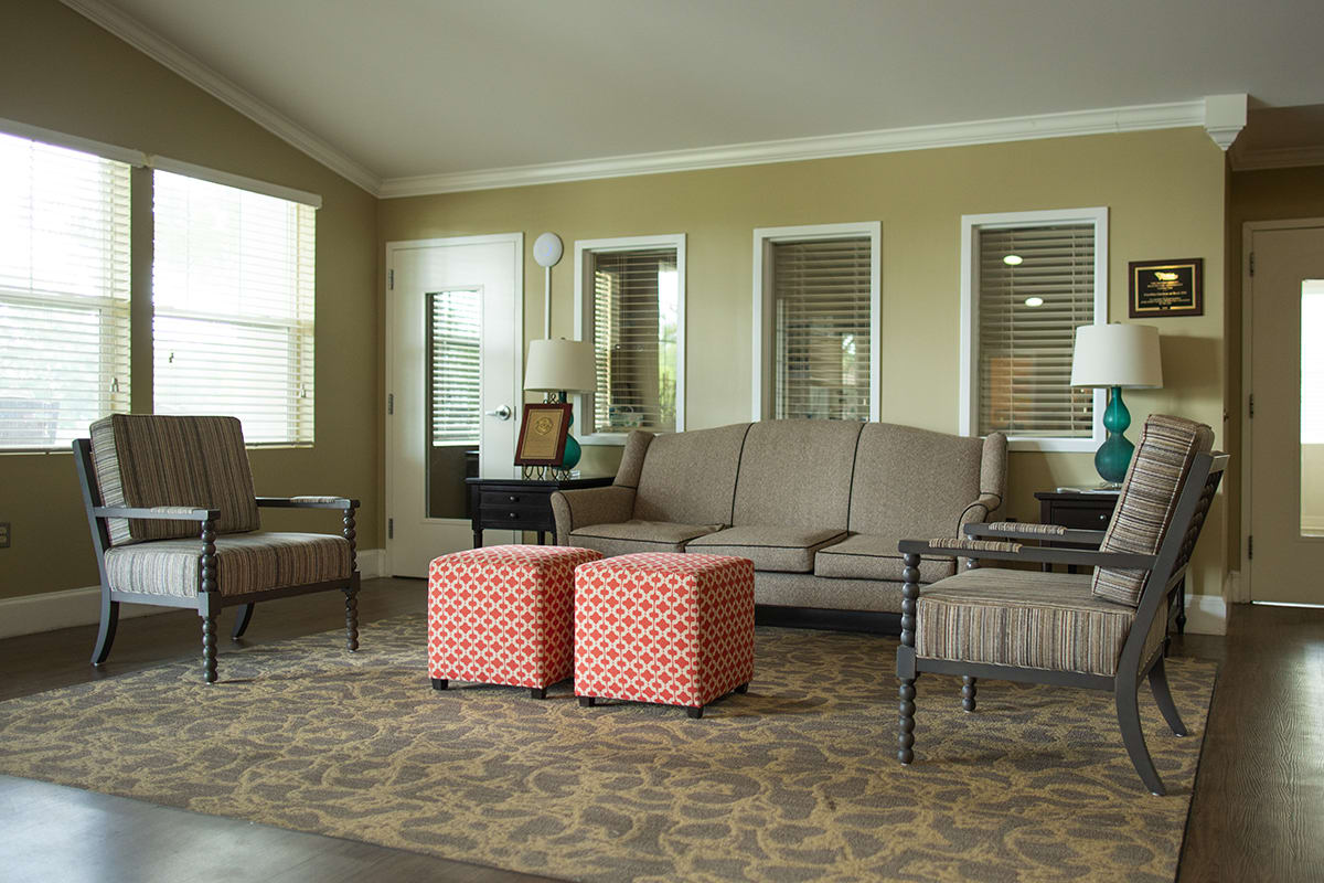 A cozy living room with a sofa, chairs, and colorful ottomans.