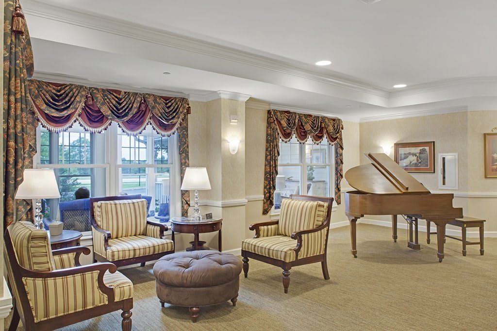 A well-furnished living room featuring elegant seating and a grand piano.