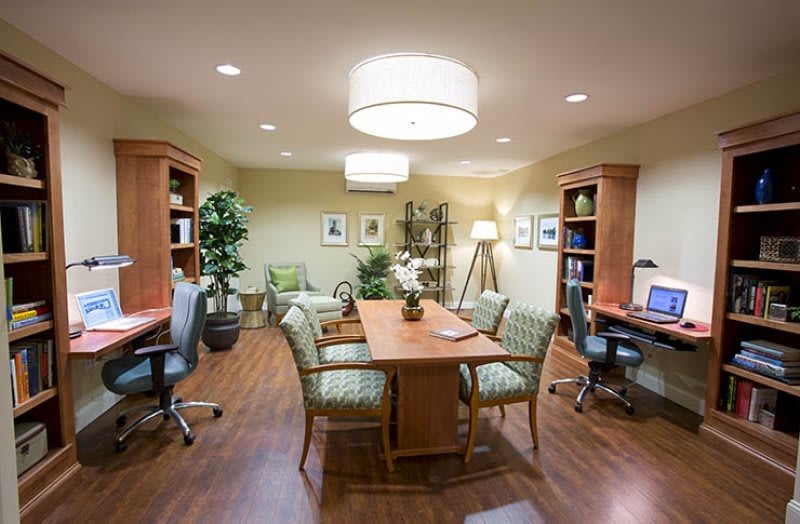 A well-organized conference room with a central wooden table, chairs, and workstations on either side.