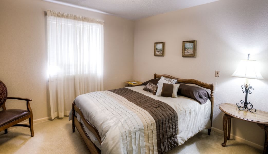 A cozy bedroom with a neatly made bed, decorative pillows, and soft lighting.