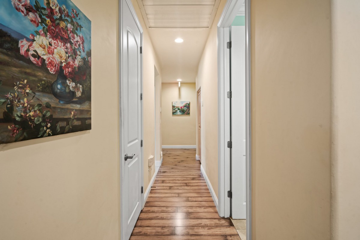 A well-lit hallway with wooden floors and paintings on the walls.