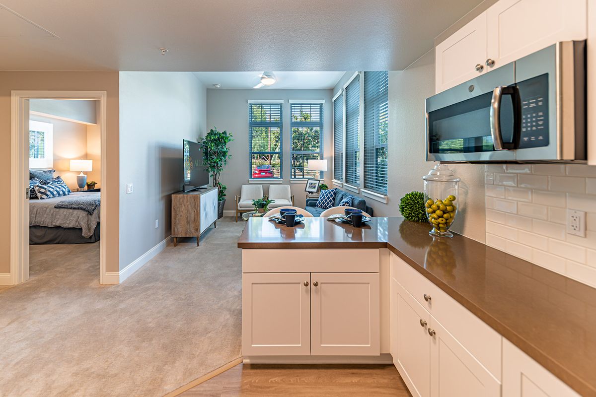 A modern open-concept kitchen and living room with natural light streaming through large windows.