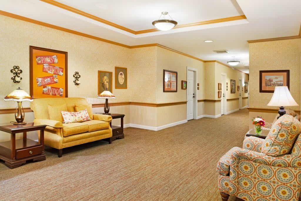 A warmly decorated hallway with comfortable seating and framed artwork on the walls.
