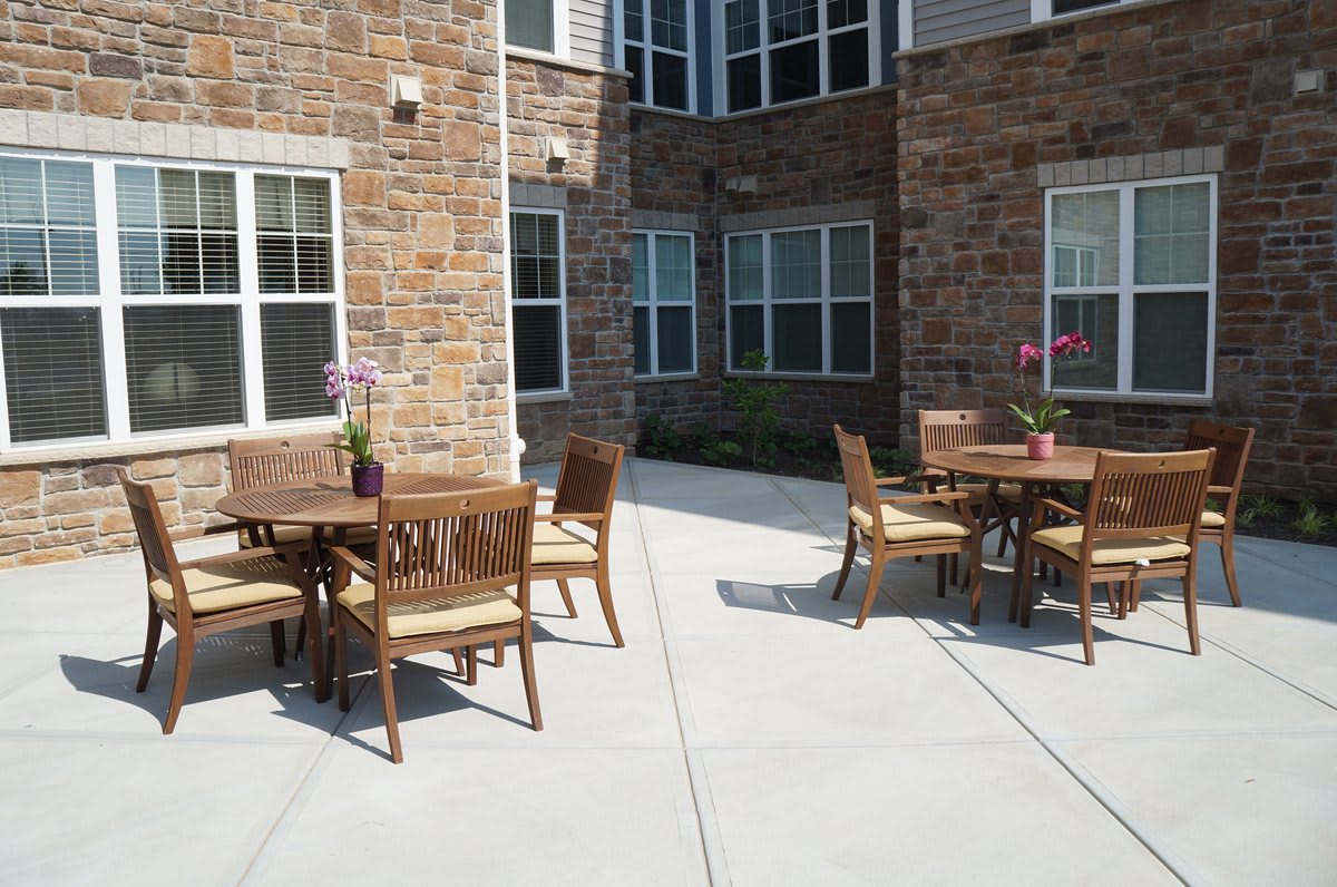 An outdoor patio with tables and chairs set against a brick building.