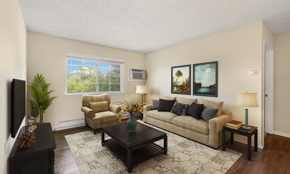 A cozy living room featuring a beige couch and armchair, a dark coffee table, decorative pillows, and two framed artworks on the wall.