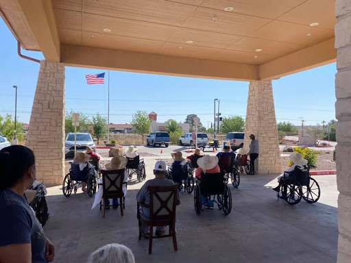 Seniors gathered in outdoor seating for an event, with a flag waving in the background.