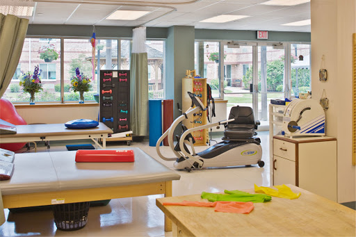 A bright and spacious physical therapy clinic equipped with various exercise tools and therapy tables.