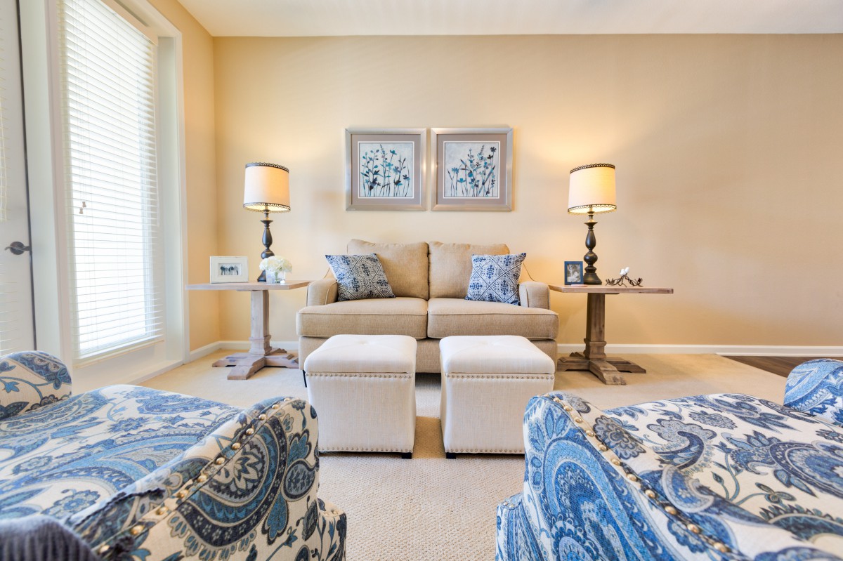 A cozy living room featuring a beige sofa, decorative pillows, matching lamps, and wall artwork.