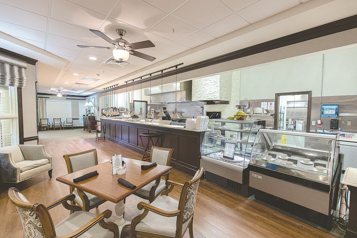 A cozy cafe interior with a mix of tables and chairs, a counter, and display cases.