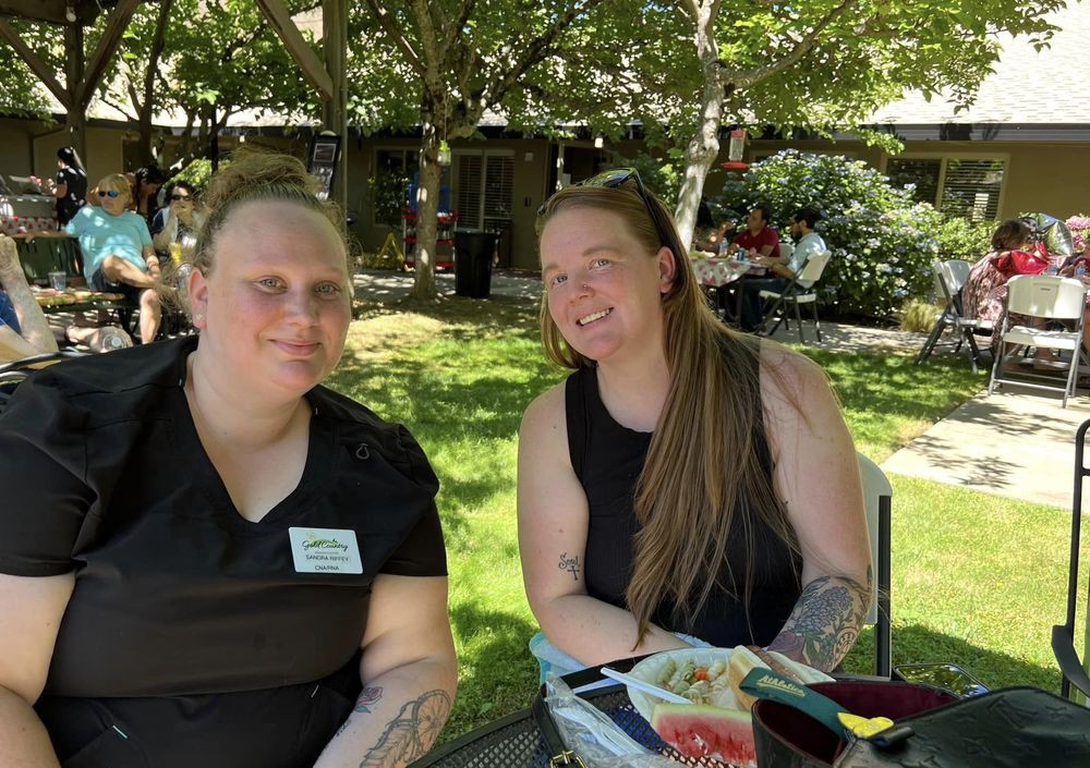 Two people sitting outside in a garden area, enjoying the sunny day.