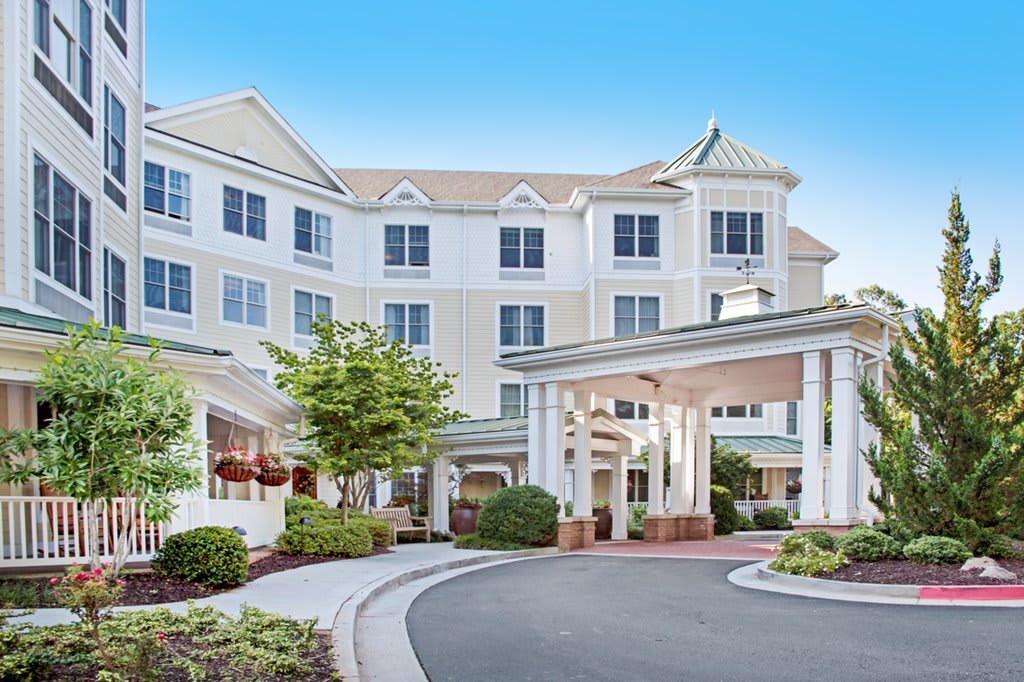A spacious hotel entrance with a circular driveway and well-maintained landscaping.