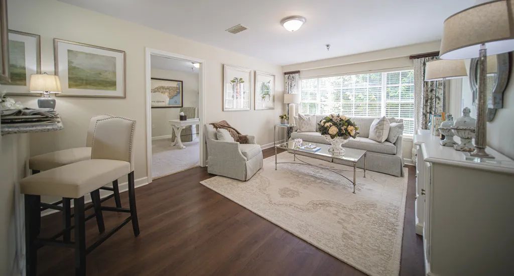 A cozy and elegantly decorated living room with a sofa, armchair, coffee table, and large window.