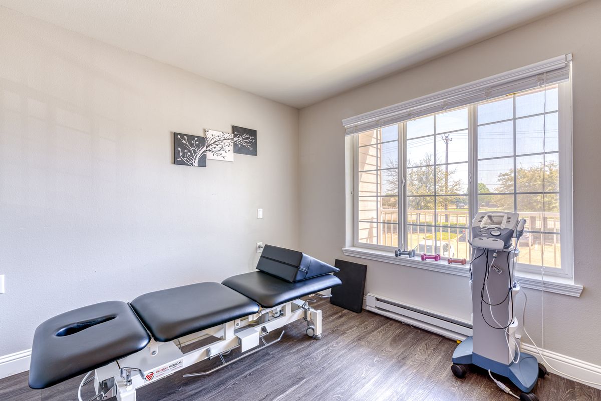 A bright chiropractic treatment room with a comfortable table and large window.