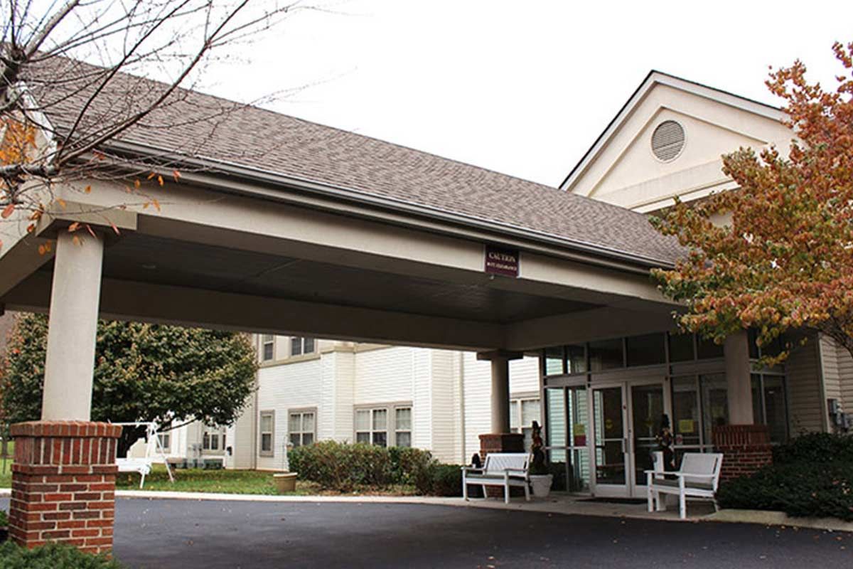 The exterior view of a building entrance with an awning and driveway.