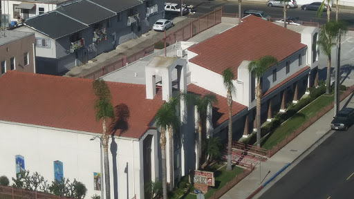 Aerial view of a building with red rooftops surrounded by palm trees.