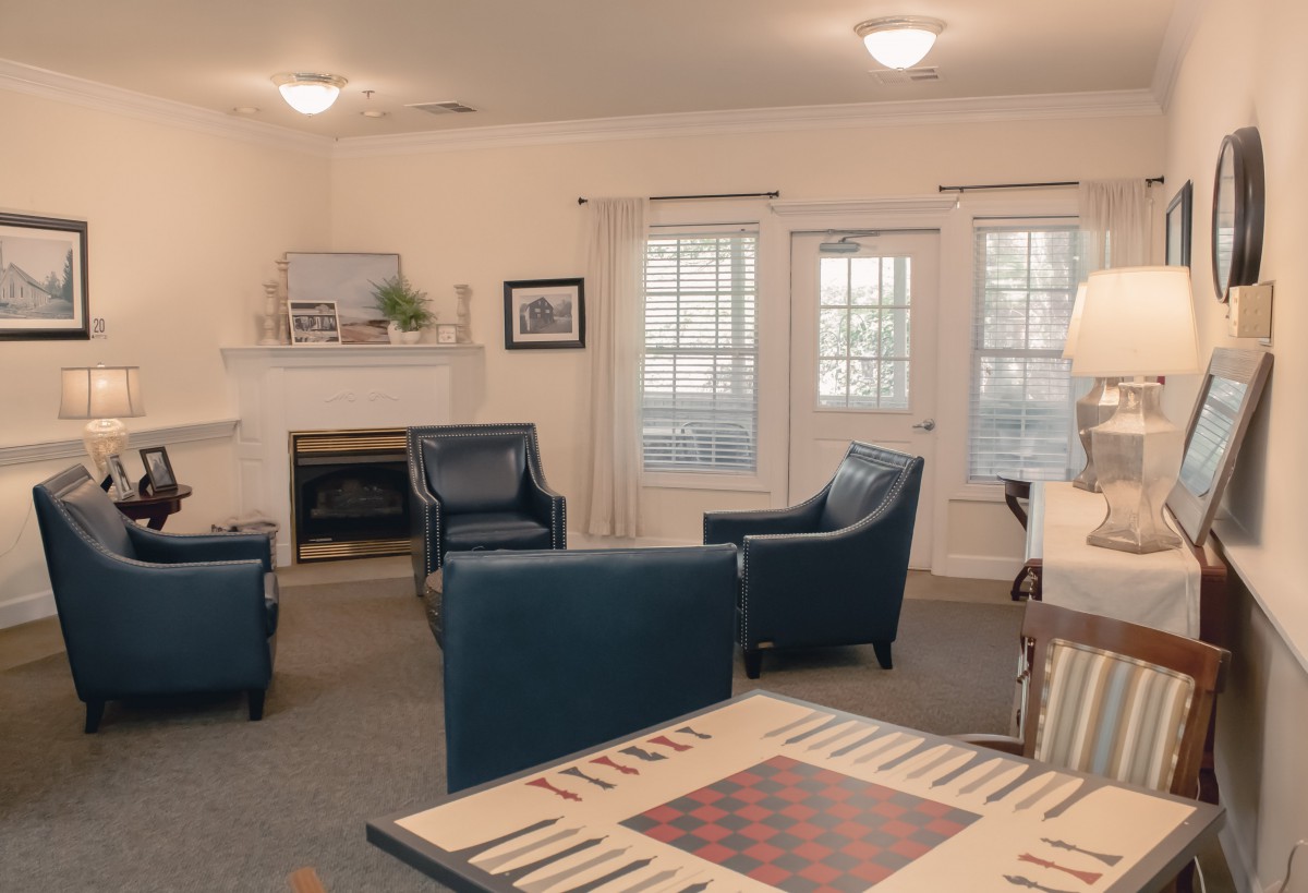 A cozy living room with blue chairs, a fireplace, and large windows.