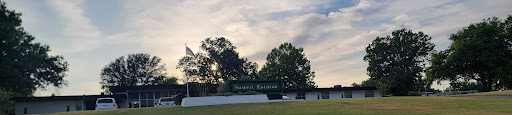A scenic view featuring a sunset behind trees and a sign.
