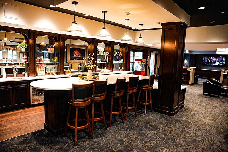 A modern bar interior with a sleek counter and wooden stools.