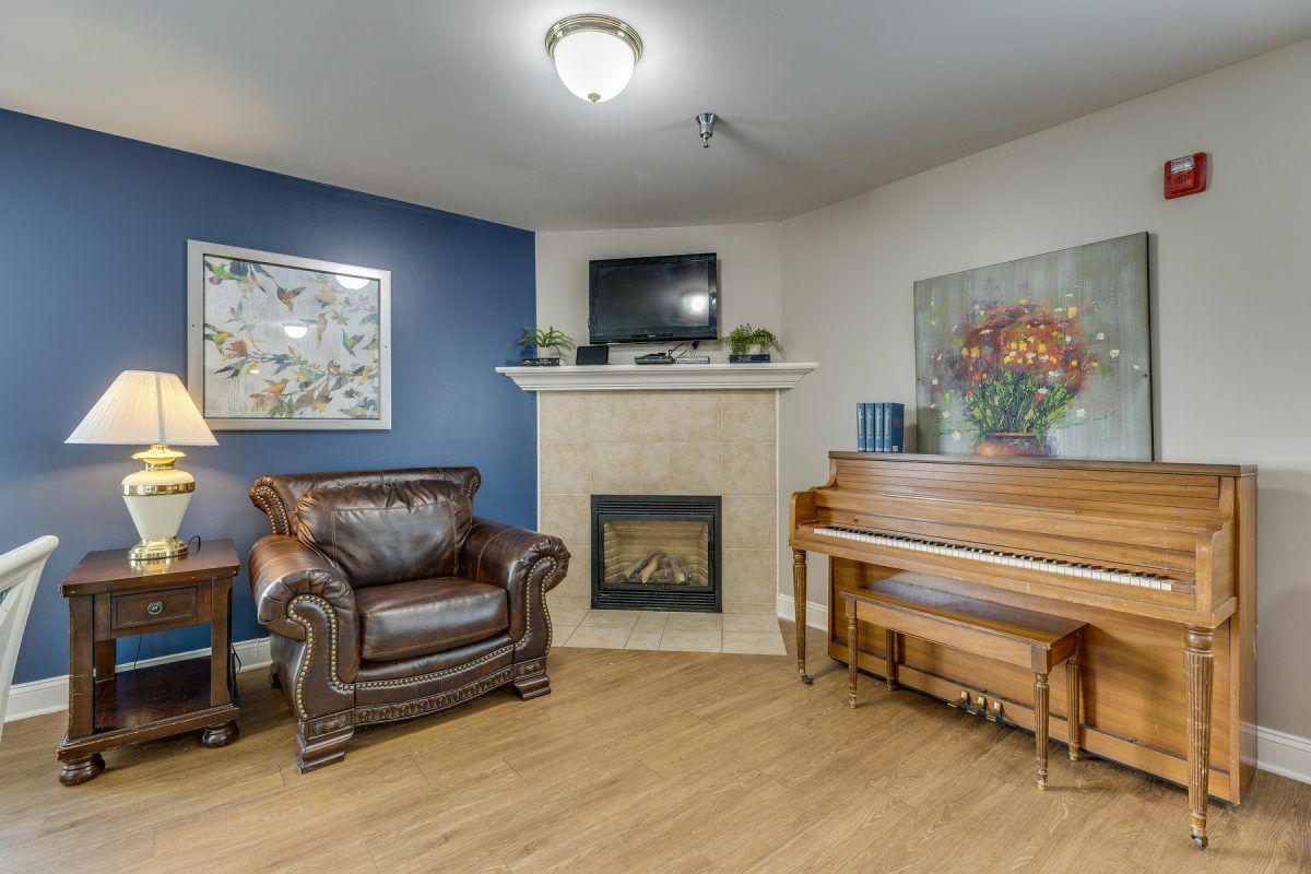 A cozy living room with a fireplace, armchair, and piano.