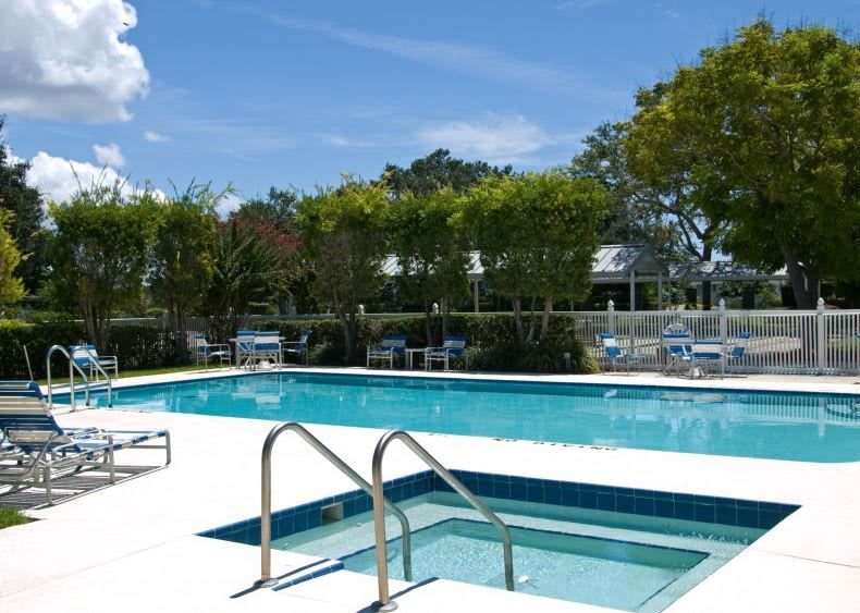 An inviting outdoor swimming pool on a sunny day, surrounded by trees.