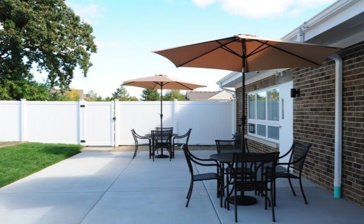 An outdoor patio with tables, chairs, and umbrellas under a clear sky.