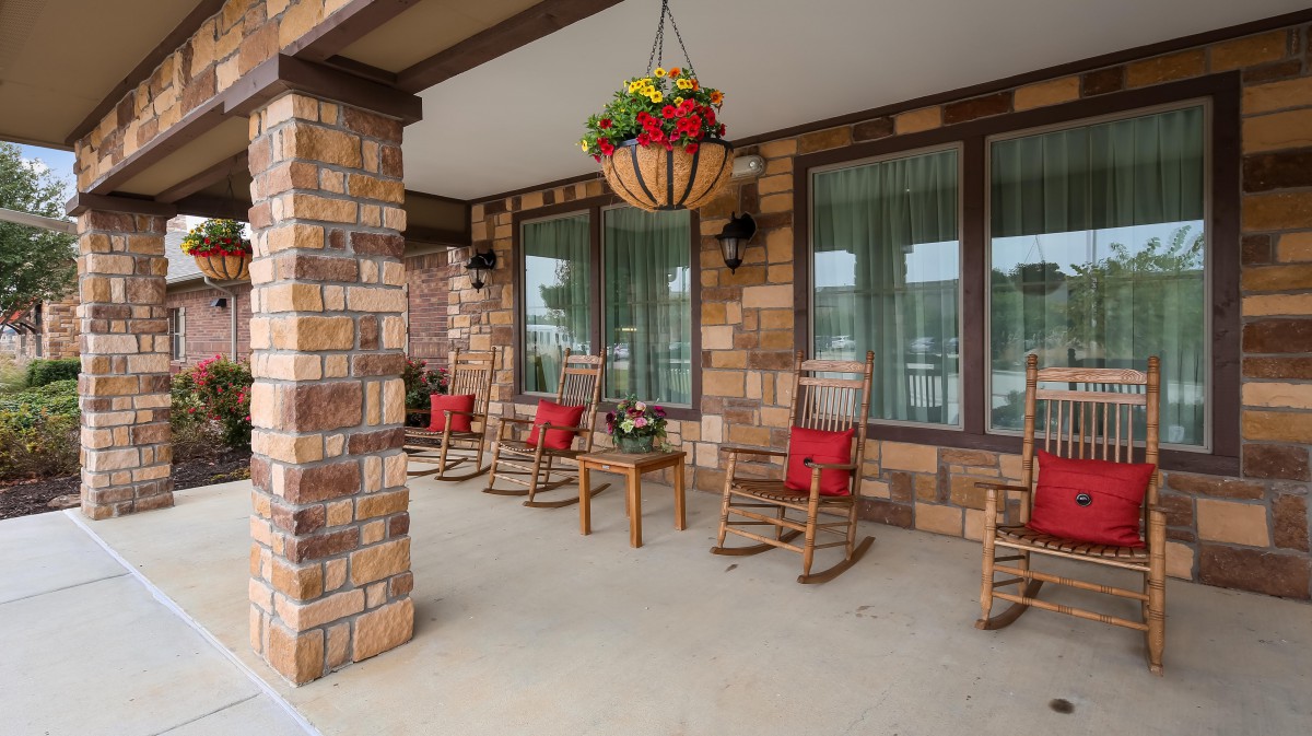 A welcoming front porch with rocking chairs and vibrant hanging plants.
