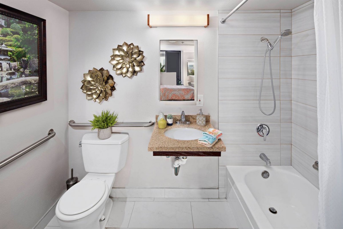 A contemporary bathroom featuring modern fixtures, decorative wall art, and a tiled shower area.