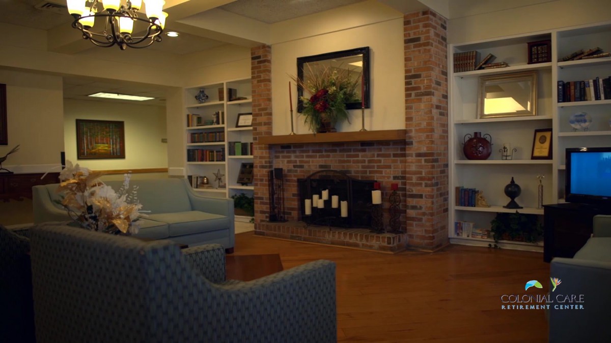 Cozy living room with a brick fireplace and shelves filled with books.
