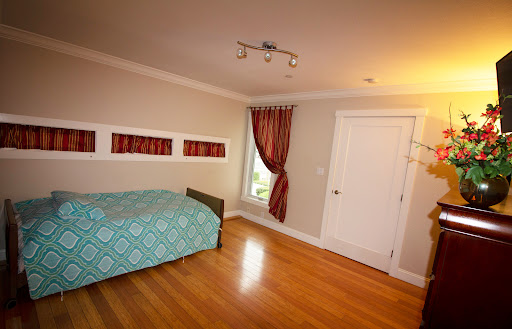 A cozy bedroom featuring a bed with a turquoise cover, elegant curtains, and wooden flooring.