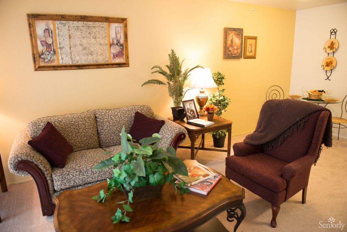 A cozy living room featuring a sofa, armchair, and coffee table with indoor plants and decor.