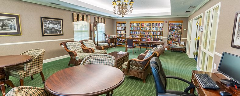 A cozy library reading room with comfortable seating and bookshelves filled with books.