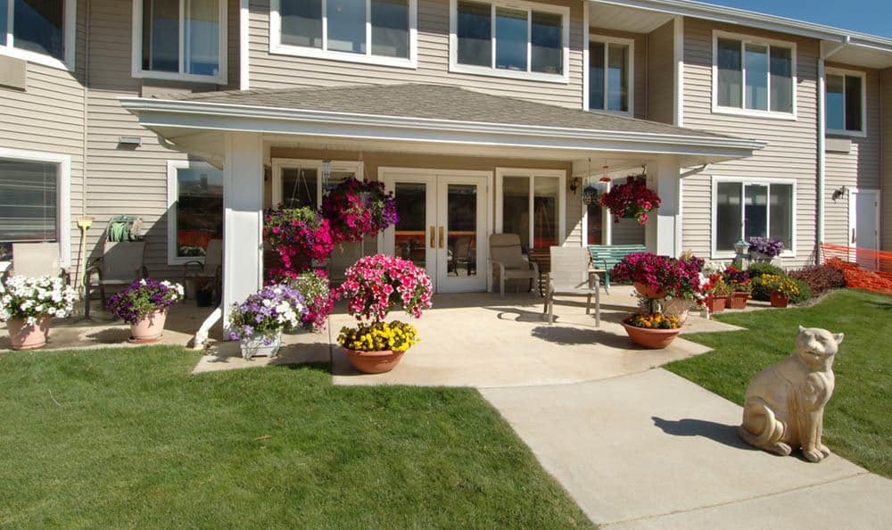 A cozy patio area adorned with vibrant flowers and comfortable seating in front of a house.