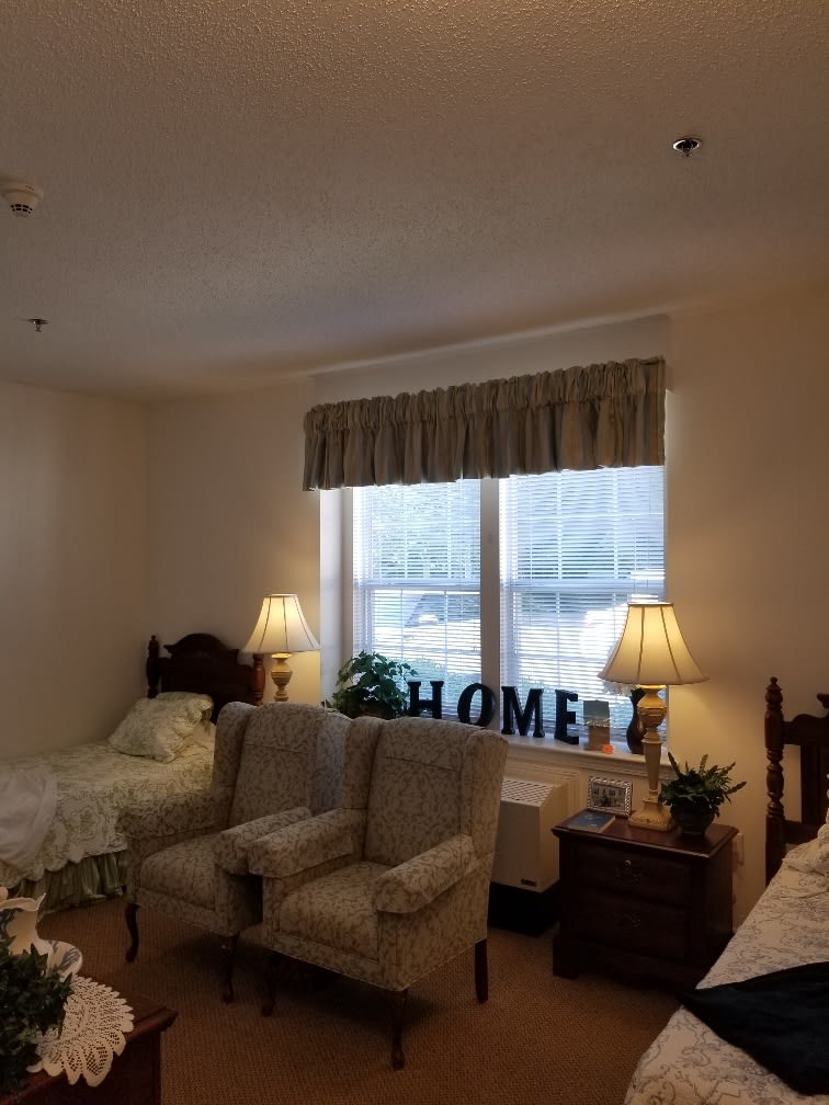 Cozy bedroom with twin beds and a sofa under a sunny window.
