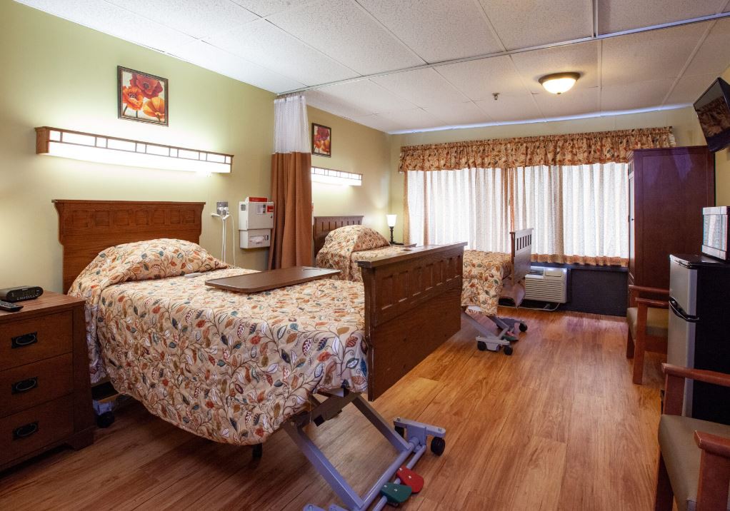 A hospital room with two patient beds and medical equipment.