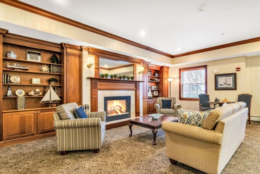 A cozy living room featuring wood paneling, a fireplace, and comfortable furniture.