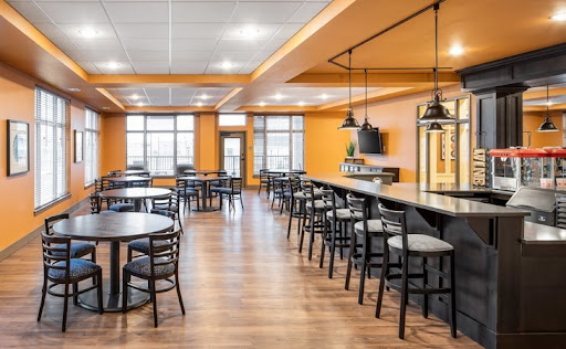 A modern dining area featuring orange walls, wooden flooring, and ample seating arrangements.