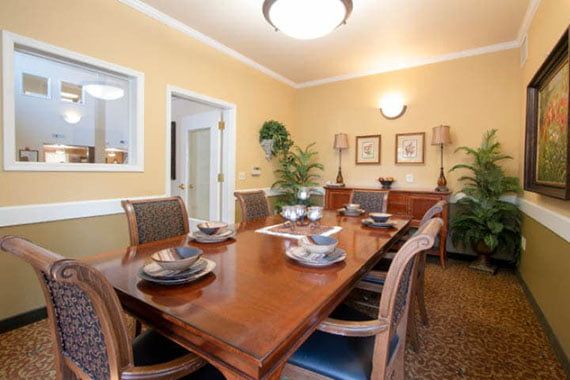 Elegant dining room with a wooden table set, decorative plants, and ambient lighting.