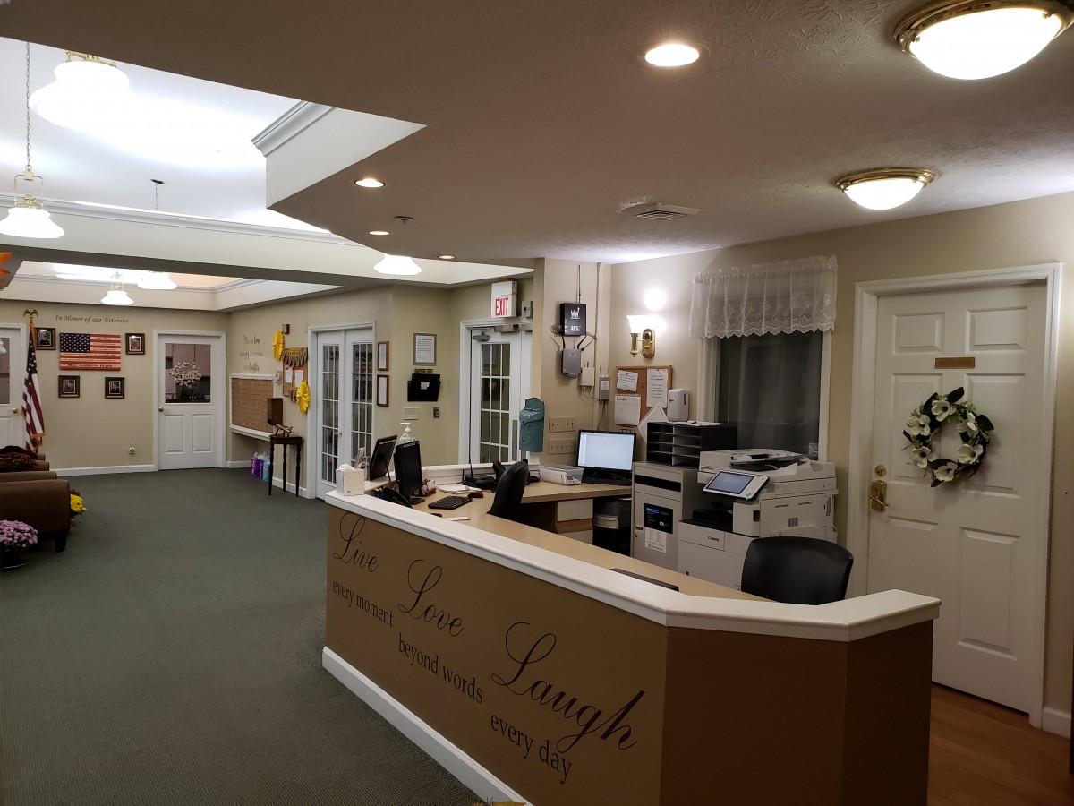 A well-lit reception area with a desk, computer, and chairs in an office setting.