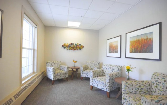 A cozy waiting room with patterned chairs and decorative art on the walls.